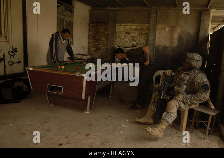 US Army Spc. Jimmie Arnold Uhren eine Partie Billard gespielt wird durch einige irakische Männer, während Soldaten der irakischen Armee und US-Armeesoldaten ein Haus für Gegenstände des Interesses an Mansour, Irak, April 10 suchen. Arnold ist der 3. zugeordnet, Platoon, Alpha Company, 2. Bataillon, 3. Infanterie-Regiment, 3rd Stryker Brigade Combat Team, 2nd Infantry Division Fort Lewis, Washington Stockfoto