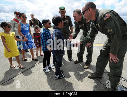 Pacific Air Forces Demo Team-Mitglieder, Generalmajor Matte Klingenber, pilot, links, und Generalmajor Chris Ross, Copilot, rechts, begrüßt Kinder von Brunei, die Königsfamilie, die c-17 Globemaster statisch auf der Flightline auf Rimba Luftwaffenstützpunkt während der 4. Biennale von Brunei Darussalam Verteidigung Weltausstellung, 4. Dezember 2013 zeigt. Gemeinsame Basis Pearl Harbor-Hickam Personal sind die c-17 Globemaster III durch statische Displays und Luftaufnahmen Demonstrationen während BRIDEX präsentiert.  BRIDEX 13 ist eine Gelegenheit für networking und sharing-Technologie mit regionalen Partnern und Verbündeten, die starke Mult baut Stockfoto