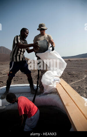 US Army Captain Justin Lev, Civil Affairs Team 4902 Team Chef, Combined Joint Task Force - Horn von Afrika, hält eine Tasche für einen Dorfbewohner zu füllen mit einer Mischung aus Schmutz, Beton und Wasser während des Baus der Eco-Kuppel hier 23 Mai. Die Arbeiter setzen Sie die Mischung in gespendeten Sackleinen-ähnliche Taschen und Stacheldraht auf jede Tasche um im Ort zu greifen, während die Mischung gehärtet platziert. Stockfoto