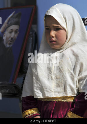 Eine junge afghanische Frau steht in der Nähe ein Foto von Präsident Hamid Karzai, Präsident der islamischen Republik Afghanistan, und hilft Platzanweiser Gäste bei der Sufiabad Schule Einweihung, 17.März. Sufiabad Schule in Herat Stadt wird ca. 1.500 Studenten zwischen Alter 7-18 in Themen wie erziehen: Dari, Mathematik, Geschichte, Geographie, Religion, Englisch, Arabisch, Physik und Leibeserziehung. Stockfoto