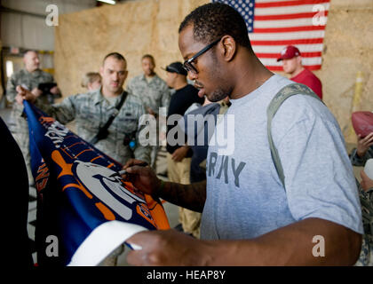 Von Miller, NFL-Denver Broncos Linebacker, Anzeichen dafür, dass eine Broncos Flagge für Staff Sgt Christopher Ingle, 376th Expeditionary Bauingenieur-Geschwader Motor 11 Crewchief, 20. März 2013, Transit Center am Manas, Kirgisistan zu retten. "Es ist ein großer Spieler aus meiner Lieblingsmannschaft zu sehen", sagte Ingle. "Ich war so aufgeregt, als ich herausfand, dass sie TCM zu Besuch waren." Ingle wird bereitgestellt von Peterson Air Force Base, Colorado, und ist ein Eingeborener von Clinton, Utah. Staff Sgt. Stephanie Rubi) Stockfoto