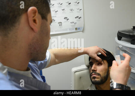 US Air Force major Michael Parsons, Augenarzt zugewiesen der 455. Expeditionary Medical Group prüft die Augenmuskeln die linke Augenhöhle eines afghanischen Soldaten vor dem Einsetzen einer Prothese in seine leere Augenhöhle während am Klinikum Craig Joint Theater in Bagram Air Field, Afghanistan, 7. August 2014. Der Soldat erlitt eine Auge Trauma als Schrapnell von einer Explosion ihn in seinen Augen vor vier Monaten traf. Parsons ist ein Eingeborener von Poughkeepsie, N.Y. und Form der 88. chirurgische Geschwader an Wright-Patterson Air Force Base, Ohio im Einsatz.  Master Sergeant Cohen A. Young Stockfoto