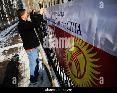 Captain Mike Reimers auflegt ein Betrieb Warm und trocken Banner 16. Januar 2012, an einem Zaun vor Emgekchil Schule in Sary-Oi, Kirgisistan. Die Verteilung der Wintermäntel und decken erfolgte während einer fünf-Tage-Mission in der Issyk-Kul Region von Kirgisistan, und mehr als 50 Zirmen aus der 376th Air Expeditionary Wing am Transit Center Manas freiwillig ihre Zeit zu unterstützen. Reimers ist der Auftraggeber Offizier für die 376th Air Expeditionary Wing Theater Security Cooperation Division Geilenkirchen Air Base in Deutschland im Einsatz. Stockfoto