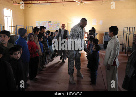 US Army Lt. Col. Wade Carmichael, Center, Executive Officer von der Farah Provincial Reconstruction Team (PRT), schüttelt Hände mit jungen in der Farah Stadt Waisenhaus in Farah, Afghanistan, 23. Dezember 2009. Mitglieder der PRT und italienische Soldaten mit Task Force South besuchte das Waisenhaus zu verteilen gespendeten Mäntel, Schuhe, Schuluniformen, Süßigkeiten und Lieferungen an die Kinder der Schule. Die PRT? s Mission war es, zu trainieren, beraten und unterstützen afghanische Staats-und Regierungschefs bei den Stadtwerken, Bezirk und Landesebene in der gesamten Provinz Farah.  Master Sergeant Tracy L. DeMarco Stockfoto