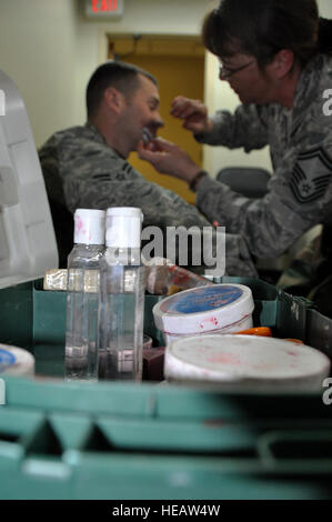 Senior Master Sgt. Tracey House, 51. Medical Support Squadron Superintendent nutzt Moulage Ausrüstung um eine simulierte Wunde am Flieger Malen 1. Klasse Jordan Glocken, 51. Geschwader Munition Munition Lehrling während Betriebsbereitschaft ausüben Beverly Bulldogge 13-02, 13. Februar 2013 in Osan Air Base, Südkorea. Glocken fungierte als ein Rollenspieler, die in einem Fahrzeug mit improvisierten Sprengkörpern gesprengt wurde. Senior Airman Kristina Overton) Stockfoto