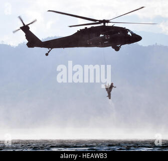 Ein Flug Medic aus Joint Task Force-Bravo 1-228. Aviation Regiment "rettet" ein Mitglied der Joint Task Force-Bravo 25. Februar 2014, aus den Wassern des Sees Yojoa, Honduras, während einer training Übung Overwater-Hebezeug. Während der Übung praktiziert Flug Sanitäter Rettung Mitglieder aus dem Wasser mit Hilfe eines Hebezeuges gesenkt von einem UH-60 Black Hawk-Hubschrauber. Capt Zach Anderson) Stockfoto