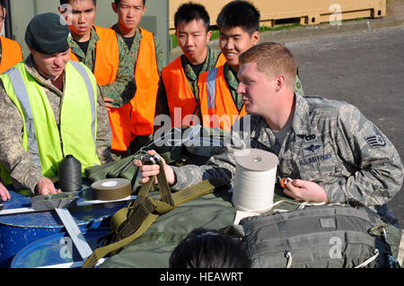 US Air Force Staff Sgt Bryan Rogers, 517th Expeditionary Airlift Squadron Bekämpfung Mobilität Spezialist, veranschaulicht, wie einen Drogue Fallschirm für die c-17 Globemaster III als Fallschirm Rigger aus drei Nationen, die zusammen für einen Gegenstand-Austausch am Royal New Zealand Air Force Base Ohakea, New Zealand, am 11. November während der zweiten jährlichen Übung Kiwi Flagge rig. US Air Force Trainer eingesetzt, um die 517th Expeditionary Airlift Squadron beigebracht Teilnehmer eine 15-Fuß-Extraktion Rutsche um die 160 Fuß Entnahmeleitung rig "für Ladung Luft sinkt aus dem c-17 Globemaster III. Die kleine Stockfoto