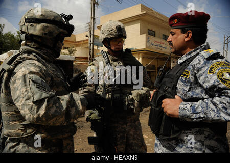 Bravo Truppe, 4. Geschwader, 9. Kavallerie-Regiment, 2. Brigade, US Army Captain Eric Dunkley (Mitte), 1. Kavallerie-Division, mit seinem Dolmetscher, Steve (links), und die irakische Nationalpolizei Oberstleutnant Mahmoud (rechts) von Salah Bataillon, Nationalpolizei von Mosul, diskutieren Verfahren für eine Mission im Stadtteil Tal Al Ruman von Mosul, Irak, 25. März 2009. Stockfoto