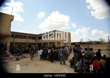 US-Soldaten von Bravo Truppen-, 4. Geschwader, 9. Kavallerie-Regiment, 2. Brigade, 1. Kavallerie-Division und irakische nationale Polizisten von Salah Bataillon, Nationalpolizei von Mosul, verteilen Schulmaterial für Schüler an einer Schule im Stadtteil Tal Al Ruman von Mosul, Irak, 25. März 2009. Stockfoto