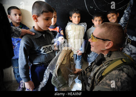 US Army Captain Eric Dunkley, Bravo Truppe, 4. Geschwader, 9. Kavallerie-Regiment, 2. Brigade, 1. Kavallerie-Division, händigt eine Tasche von Schulmaterial, ein Schüler von Khalid Schule im Stadtteil Tal Al Ruman von Mosul, Irak, 25. März 2009. Stockfoto
