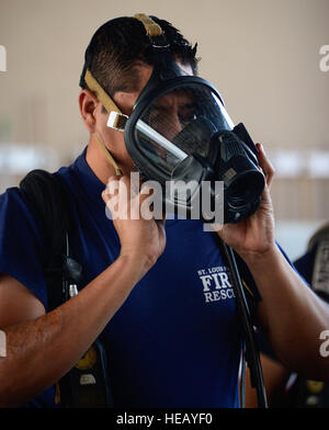 Ein Feuerwehrmann aus El Salvador versucht auf eine Atemmaske während der umluftunabhängiges Apparat Orientierung gegeben durch die 612th Air Base Squadron Feuerwehrleute während El Salvadors autonomen Hafen Kommission Flughafen Feuerwehrmann Leben-Brände auf Soto Cano Air Base, Honduras, 3. Dezember 2014. Der 612th ABS-Feuerwehr erleichtert El Salvadors Port Kommission Flughafen Feuerwehrmann Qualifikation durch die Bereitstellung von live-Feuer. El Salvador Flughafen-Feuerwehr haben eine Anforderung sehr ähnlich zu den Standards der Vereinigten Staaten, die Mitglieder von ihrem Flughafen-Feuerwehren werden benötigt Stockfoto