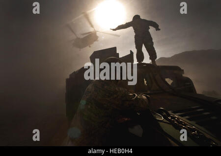 US Army Staff Sgt Hector Hoyas, Aerial Delivery Service Feldabteilung Ausbilder aus Fort Lee, VA., Wellen aus einem Nevada Army National Guard 1/189 Aviation Company CH-47 Chinook-Hubschrauber als US Air Force Piloten von 820th Red Horse Geschwader in der Luft Flug sichern den Spiegel vor dem Einhängen der Humvee bis zu der Chinook für Schleuder-Last auf Nellis Air Force Base , Nevada, April 15. Der Nevada Army National Guard, ADFSD und die 820th in der Luft fliegen durchgeführt Abwürfe und Sling-Last Training. Stockfoto