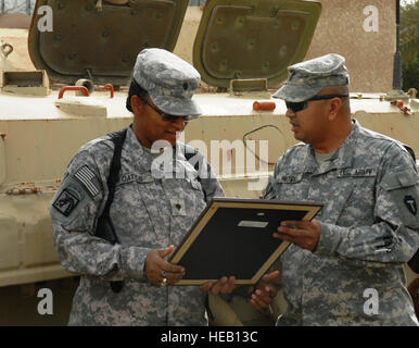 SPC. Verna Oates (links), von Texarkana, Texas, serviert mit Headquarters und Headquarters Company, 56. Infanterie Brigade Combat Team, 36. Infanterie-Division, Multi-National Division-Bagdad, erhält gerahmte Kopie der Militärinternat Offizier Creed von 1st Sgt. Ron Novio, senior eingetragen führend für HHC, 56. IBCT während einer Promotion-Zeremonie im Camp Sieg am 14. März. Oates, gefördert unter dem Feld Förderung Kampfsystem verdienende, förderfähigen Soldaten für eine Beförderung nach entweder Feldwebel, Feldwebel, wählt die war neun Jahre im aktiven Dienst, mit fast sieben Jahre lang in Stockfoto