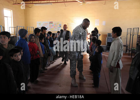 Executive Officer für Farah Provincial Reconstruction Team (PRT), US Army Lt. Col. Wade Carmichael schüttelt Hände mit den Jungs im Farah Stadt Waisenhaus während eines Besuchs in Gegenstände gespendet von lokalen afghanischen Auftragnehmern, 23. Dezember 2009, Farah, Afghanistan zu verteilen. Neben austeilen Kleidungsstücke und Schulmaterial, die International Security Assistance Force-Mitglieder aus der FHM und italienischen Task Force Süd vorausgesetzt medizinische Versorgung für diejenigen, die brauchen Sie es, bevor Sie sich für eine Pizza zu Mittag mit den Kindern. Stockfoto