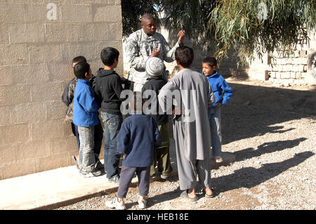 Lt. Col Wade Carmichael, Executive Officer von der Farah Provincial Reconstruction Team (PRT), zeigt die klassische Luftgitarre für einige der jungen, die im Waisenhaus Farah Stadt, 23. Dezember 2009, Farah, Afghanistan leben.  Während des Besuchs in das Waisenhaus das PRT und Task Force Süd abgesetzt $5.000 Wert der Elemente, die für die Kinder von 10 lokalen afghanischen Unternehmern gespendet wurden und auch einige Zeit mit den Kindern genießen konnten. Stockfoto