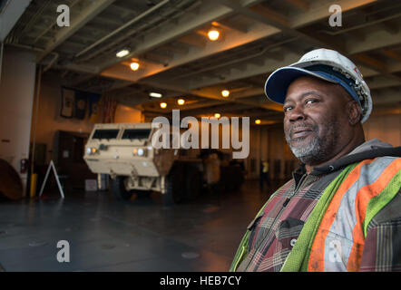 Robert Heyward, International Hafenarbeiter Association Flagman, hält eine Mine Resistant Ambush Protected Fahrzeug auf Station an Bord der USNS Pomeroy (T-AKR-316), 10. Januar 2014, auf der gemeinsamen Basis Charleston - Weapons Station S.C Die Pomeroy ist eine der 19 groß, Mittel Roll-on und Roll-off-Schiffe der Marine Military Sealift Command. Senior Airman Ashlee Galloway) Stockfoto