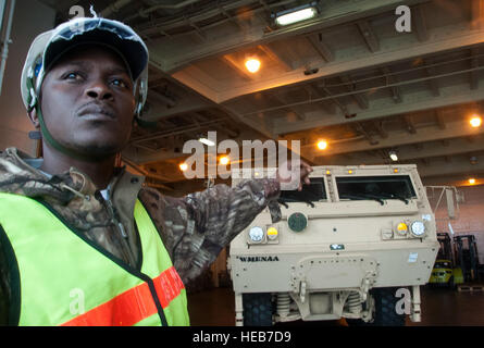 Darriel Porcher, International Hafenarbeiter Association Flagman, leitet einen LKW, wie es von der USNS Pomeroy (T-AKR-316), 10. Januar 2014 off-loaded ist. Die Pomeroy enthält Sustainment Brigade Sets bestehend aus Lieferungen von Tanklastwagen, Gabelstaplern, Schädlinge, Frachtcontainer, unwegsames Gelände Containerstapler und Munition. In diesem Jahr soll das 841st Transport-Bataillon vier Armee vorpositioniert Lager Schiffe aufzunehmen. Staff Sgt William O'Brien) Stockfoto