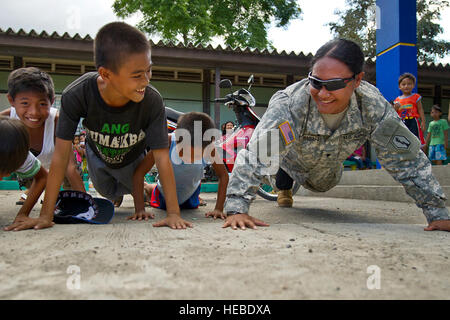 US Army Spc. Petina Pulemagafa,(right) 740th Combat Support Unternehmen, 100. Bataillon Infanterie-Regiment, macht Liegestütze mit lokalen philippinischen Kindern während Balikatan 2012 April 21 in Callos Elementary School in Barangay Callos in der Provinz Nueva Ecija, Philippinen. Soldaten aus dem 871st Ingenieur-Unternehmen, 411th Engineer Battalion und bewaffnete Kräfte der Philippinen 7. Infanterie-Division, arbeiten mit Einheimischen, die Schule undichtes Dach zu reparieren. Übung Balikatan ist eine jährliche Veranstaltung von Schulungen zur Verbesserung der gemeinsamen Planung, Kampfbereitschaft, humanitäre Hilfe und inter Stockfoto