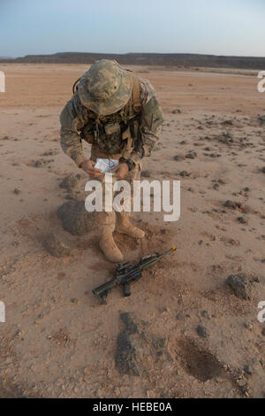 Ein Soldat vom 1. Bataillon, 77. Armored Regiment, 3rd Armored Brigade Combat Team, 1. US-Panzerdivision, prüft seine Karte, die Nutzung des verfügbaren Lichts während der nächtlichen Land Navigation Teil des Studiengangs US Armee-Experte Infanterist-Abzeichen in Dschibuti, 20. April 2015. Die EIB ist eine besondere Fähigkeiten Abzeichen der U.S. Army Soldaten halten Infanterie oder Spezialeinheiten militärische berufliche Spezialitäten nach der Fertigstellung des spezifischen Voraussetzungen und eine Reihe von abgestuften Tests auf grundlegenden Infanterie Fähigkeiten verliehen. (Foto: U.S. Air Force Staff Sgt Gregory Brook / veröffentlicht) Stockfoto