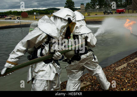 Feuerwehr manövrieren ein Feuerwehrschlauch um Brände, zur Unterstützung der Krieger Übung 86-13-01 (WAREX) angreifen / Übung Global Medic 2013, Fort McCoy, Wisconsin, USA, 27. Juli 2013. WAREX bietet Einheiten die Möglichkeit, militärische Manöver und Taktiken zu üben. In Verbindung mit WAREX gehalten, übt sich Global Medic jährliche Gelenk-Bereich Ausbildung entwickelt, um alle Aspekte der medizinischen Kampfunterstützung Theater zu replizieren. (US Air Force Foto von Staff Sgt. Jared Becker/freigegeben) Stockfoto