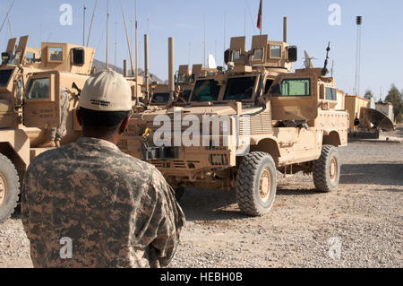 US Army 1st Sgt Steven Clark, der 1st Sgt. von der Farah Provincial Reconstruction Team (PRT), schaut zu, wie Forward Operating Base (FOB) Farah von einer dreitägigen Mission nach Herat, Afghanistan, vier neue mir beständig Hinterhalt geschützt (MRAP) Fahrzeuge, 1. Februar 2010 abzurufenden Mitgliedern seiner Einheit zurückkehren.  MRAPs verfügen über ein "V" geformt Rumpf, die entworfen, um ihren Passagieren vor Explosionen aus unter dem Fahrzeug, wie z. B. Improvised Explosive Devices (IED) zu schützen. Stockfoto