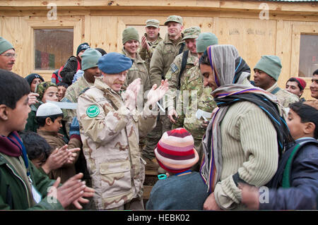 Niederländischen Oberst Kees Marselis, Mitte links, Stabschef der Kandahar Flugplatz begrüßt einen afghanischen junge für Durchschneiden des Bandes für die neue Kandahar Flugplatz Basar Schule während einer Zeremonie an der Basis in Kandahar, Afghanistan, 21. Januar 2012. Die Schule war für Studierende, deren Eltern auf dem Basar auf Basis gearbeitet. Freiwillige bei der US Air Force 809th Expeditionary schnelle Ingenieur einsetzbare schwere operative Reparatur Squadron Ingenieure nach es im Oktober 2011 brannte die Schule umgebaut. (US Air Force Foto von Staff Sgt. David Carbajal/freigegeben) Stockfoto