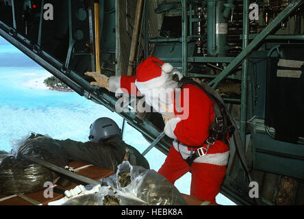 Sehen Sie Santa Clause (Captain Mike Albertis, 605th militärischer Luftbrücke Support Squadron) und Staff Sgt Tony Thompson, Loadmaster mit der 21. Tactical Airlift Squadron, zu, wie ein Weihnachten fallen Container in Richtung Bestimmungsort abgesprungen ist.  Die jährliche Airdrop ist eine humanitäre Hilfeleistung für bedürftige Inselbewohner in Mikronesien während der Ferienzeit. Stockfoto