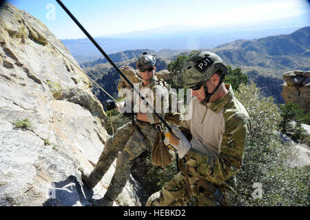 Von links beobachtet US Air Force Staff Sgt Lucas Gough, ein Pararescueman mit 48. Rescue Squadron (RQS), Oberst Tschad Franken, der Kommandeur der 23. Flügel, wie er während der hohen Winkel, Rope Rescue training am Mount Lemmon in der Nähe von Tucson, Arizona, 12. Februar 2014 eine Klippe hinunter steigt. Franks besucht die 48. RQS als Teil einer Outreach Tour von geografisch getrennten Einheiten unter seinem Befehl. (Foto: U.S. Air Force Airman 1st Class Betty R. Chevalier/freigegeben) Stockfoto