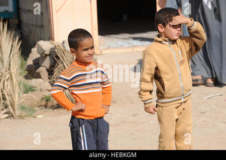 Irakische Kinder beobachte, wie US-Soldaten und Soldaten bilden Irak und El Salvador, 5. November 2008 durch ihr Dorf Al Thuesat in Al Hayy, Irak, weitergeben.  Die El salvadorianischen Armee zusammen mit der irakischen Armee und US-Armee, um humanitäre Hilfe zu leisten.  (US Air Force Foto von Staff Sgt. Rasheen A. Douglas/freigegeben) Stockfoto