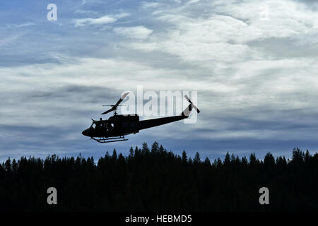 Ein UH-1N Iroquois Hubschrauber aus der 36. Rettungsflug Pässe über eine Flora und Fauna auf der Suche nach einer sicher mögliche Wasser Landezone für 336th Trainingsgruppe Bekämpfung Rettung Offiziere, ihre Freifall Schwimmer Einsatz bei einem Wasser Operations training Szenario 17. Oktober 2014, am Long Lake, Washington zu üben. 36. RQF unterstützt die 336th TRG durch praktische Hubschraubereinsätze für mehr als 3.000 Studierende pro Jahr. Training ist das ganze Jahr über zu Fairchild und an der Schule Feld Ort im Colville National Forest, ca. 60 Meilen nördlich von der Basis durchgeführt. Flugbetrieb gehören Stockfoto