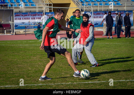 Service und Qatar Emiri Air Force Mitglieder spielen ein Freundschaftsspiel der Fußball im Qatar National Sports Day auf Al Udeid Air Base, Katar, 11. Februar 2014. Zum ersten Mal wurden mehr als 100 Soldaten, Matrosen, Soldaten, Marines und Zivilisten eingeladen, an der Veranstaltung teilnehmen, spielen Basketball, Fußball und Volleyball mit ihren Host Nation Gegenteile. Die Qatar National Sports Day ist eine Initiative angenommen im Jahr 2011 durch den aktuellen Emir, Scheich Tamim bin Hamad Al Thani, weitere Werte des Sports in der Nation Kultur einbinden und inspirieren die Menschen gesund und greifen in physischen activit Stockfoto