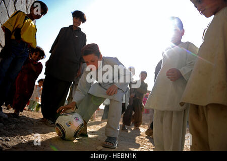 Ein afghanischer Junge zeigt seinen Freunden einen Fußball Trick beim Spiel in Qalat Stadt, Afghanistan, Sept. 25. Fußball wird häufig in den Straßen von Qalat Stadt wegen der Popularität des Sports gespielt. Stockfoto