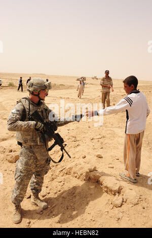 US Army Spc. Derek Weige aus den 25. spezielle Truppen Bataillon Sicherheitsabteilung, 25. Infanterie-Division, Händen candy einen irakischen Jungen während einer Untersuchung vor Ort in Al Khanik, Irak, Aug. 12. Stockfoto