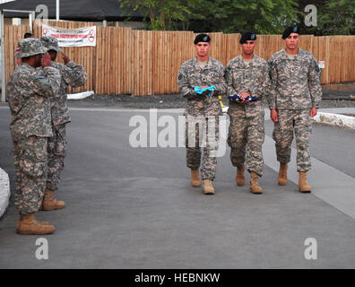 Soldaten begrüssen die amerikanische Flagge als Auszeichnung Wächter Mitglieder aus der 1/65. Infanterie-Bataillon Alpha Company in den Ruhestand die Flagge für die Nacht. Die 1/65., eine Nationalgarde Einheit bereitgestellt aus Puerto Rico, bietet Sicherheit für das Lager und führt die täglichen Tagwache und Rückzug Zeremonien hier. Die Zeremonien, Tagwache am Morgen und Rückzug am Nachmittag werden durchgeführt, um die amerikanische Flagge Respekt zollen. Während einer Zeremonie, Rückzug sollten alle Service-Mitglieder in Sichtweite oder Ton zu Ohren gekommen, und Rendern den entsprechenden Salute. Stockfoto