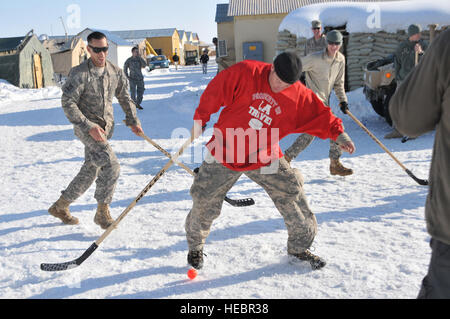 Provinz GHAZNI, Afghanistan – Ghazni Provincial Reconstruction Team Mitglieder eine kleine Auszeit, genießen die Sonne und Schnee mit einem Spiel Streethockey am 14. Februar. US Army Spc. Ross Dalton aus Yarmouth, Massachusetts, (Mitte in rot) nimmt den Ball mit US Armee Schutzzertifikate. Marcelo Gomes (links) und Benjamin Cote, beide aus Sudbery, Massachusetts, in der Verfolgung. Alle sind von Unternehmen D, 1. Bataillon, 1. Zug, 181. Infanterie-Regiment, der Massachusetts Nationalgarde mit Sitz in Hudson, Massachusetts (Foto: U.S. Air Force Chief Master Sgt. Julie Brummund, Ghazni Provincial Reconstruction Team) Stockfoto