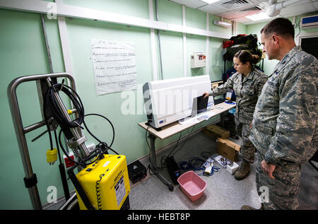 Staff Sgt Jennifer Thompson, 376th Expeditionary Praxisgemeinschaft diagnostische Bildgebung Techniker, zeigt x-ray Expeditionsfähigkeiten zu Oberst John Millard, 376th Air Expeditionary Wing Commander bei Transit Center am Manas, Kirgisistan, 8. Januar 2014. Die mobile x-ray Maschine und kann an einen anderen Ort, so dass es nützlich, wenn Flexibilität Schlüssel ist gedreht werden. Thompson wird bereitgestellt von Wright-Patterson Air Force Base, Ohio, und ist ein Eingeborener von Liberty, Indiana (U.S. Air Force Photo/Senior Airman George Goslin) Stockfoto