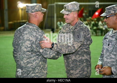 US Army Lieutenant Colonel Jason Wolter (Mitte), 1. kombiniert Arme Bataillon, 63. Armor Regiment Kommandant Reißzwecken auf Captain Sam Curry, 1. kombiniert Arme Bataillon, 63. Armor Regiment Echo-Kompanie-Kommandant, während einer Zeremonie auf den Rasen, Camp Lemonier, Dschibuti, 27. Juli 2013. Etwa 350 Soldaten wurden während der Zeremonie ihrer Bekämpfung Patch vorgestellt. Nur Soldaten, die in einer Kampfzone bereitgestellt haben sind berechtigt, einen Patch auf ihrer rechten Schulter zu tragen. (U.S. Air Force Photo/techn. Sgt Chad Thompson) Stockfoto