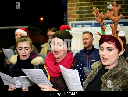 Marie Curie Cancer Charity Freiwilligen singen Weihnachtslieder in einem Zug station Plattform, Farnham, Surrey, UK. Stockfoto