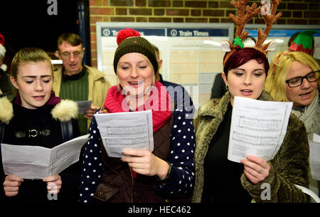 Marie Curie Cancer Charity Freiwilligen singen Weihnachtslieder in einem Zug station Plattform, Farnham, Surrey, UK. Stockfoto