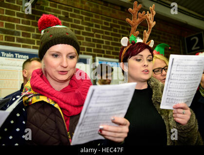 Marie Curie Cancer Charity Freiwilligen singen Weihnachtslieder in einem Zug station Plattform, Farnham, Surrey, UK. Stockfoto