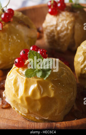 Hausgemachter Bratapfel mit frischen roten Johannisbeeren und Minze Makro auf einem Teller. vertikale Stockfoto