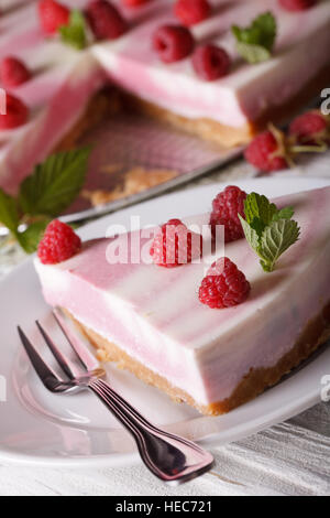 Stück rosa Käsekuchen mit Himbeeren und Minze Nahaufnahme auf einer Platte. vertikale Stockfoto