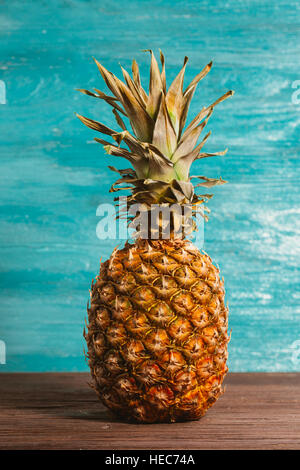 Ananas ist auf dem Tisch aus Holz blau hinterlegt. Stockfoto