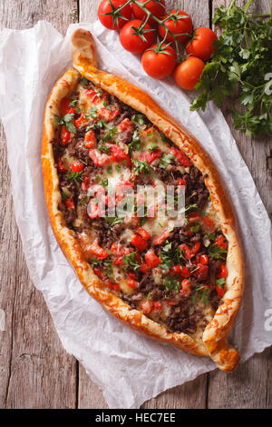 Türkische Pide-Pizza mit Fleisch und Gemüse Nahaufnahme auf dem Tisch. vertikale Ansicht von oben Stockfoto