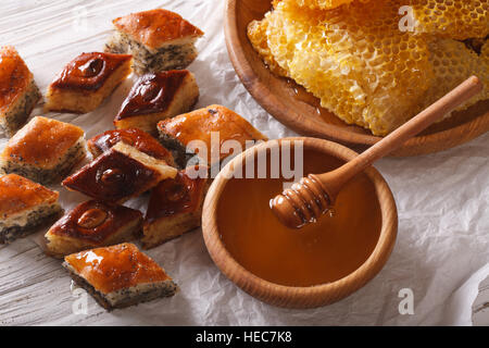 Orientalische Süßigkeiten: Baklava mit Mohn Samen und Nüssen Nahaufnahme auf einem Tisch und einer Honigwabe angeordnet. horizontale Stockfoto