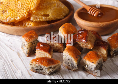 Baklava Honig mit Mohn Samen und Nüssen Nahaufnahme auf einem Tisch und einer Honigwabe angeordnet. Horizontale Stockfoto