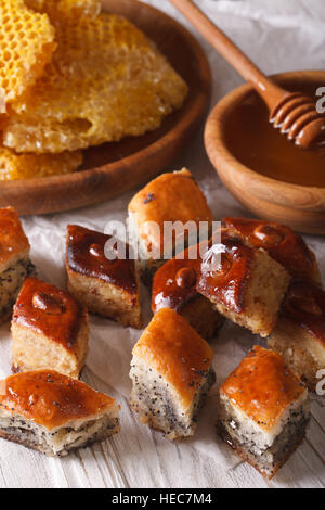 Baklava Honig mit Mohn Samen und Nüssen Nahaufnahme auf einem Tisch und einer Honigwabe angeordnet. vertikale Stockfoto