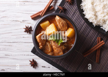 Thailändischen Massaman curry mit Huhn in eine Schüssel geben und Reis auf dem Tisch. horizontale Ansicht von oben Stockfoto