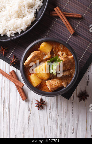 Thailändischen Massaman curry mit Huhn in eine Schüssel geben und Reis auf dem Tisch. vertikale Ansicht von oben Stockfoto