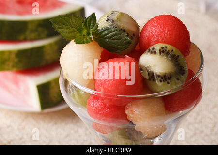 Sommer-Dessert: Obst-Kugeln aus Wassermelone, Kiwi und Melonen mit Minze in einer Glas-Nahaufnahme. horizontale Stockfoto